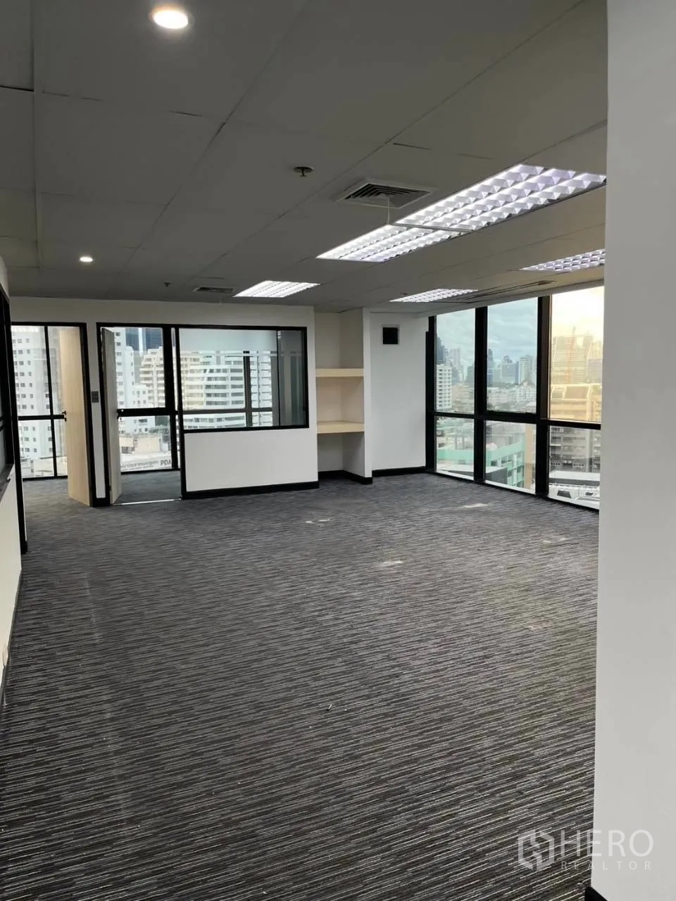 Office Space for rent in Khlong Toei, Bangkok - Large open-plan office with floor-to-ceiling windows and a built-in shelf.