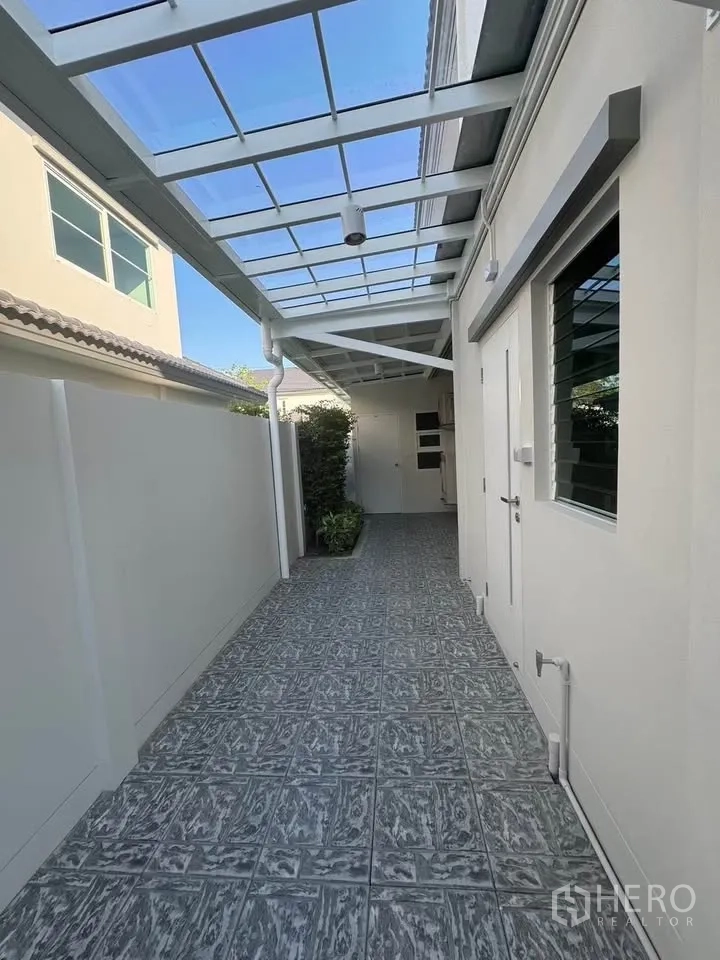 Detached House for rent in Bang Phli, Samut Prakan - Covered side walkway with translucent roof and tiled floor beside the house.