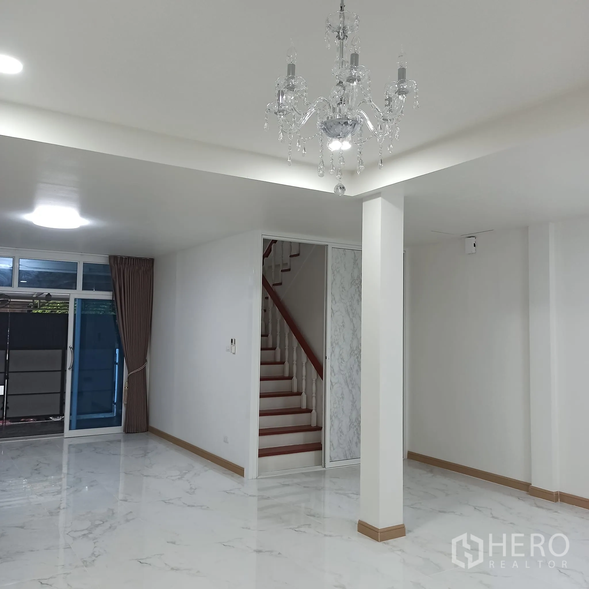 Townhouse for rent in Wang Thonglang, Bangkok - Living room with staircase and glossy white floor tiles.