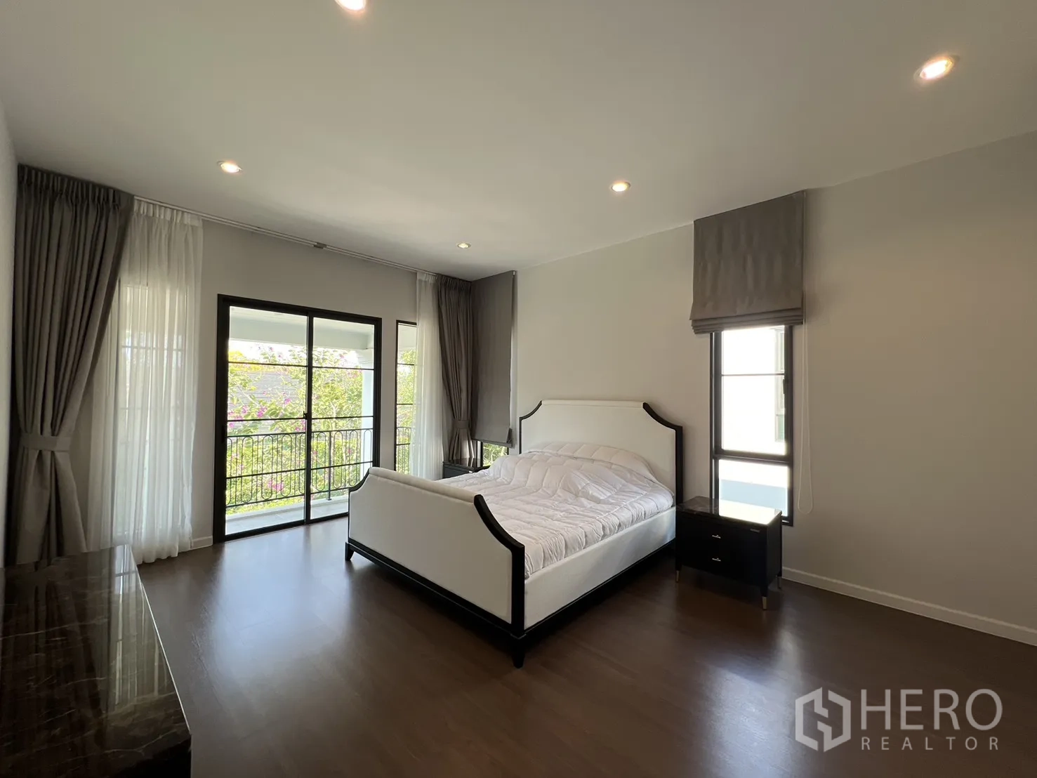 Detached House for rent in Bang Phli, Samut Prakan - Bright bedroom facing a balcony with large windows and wood flooring.