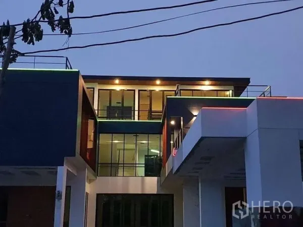 Detached House for rent in Phra Khanong, Bangkok - Night view of the facade with floor-to-ceiling windows and warm exterior lighting.