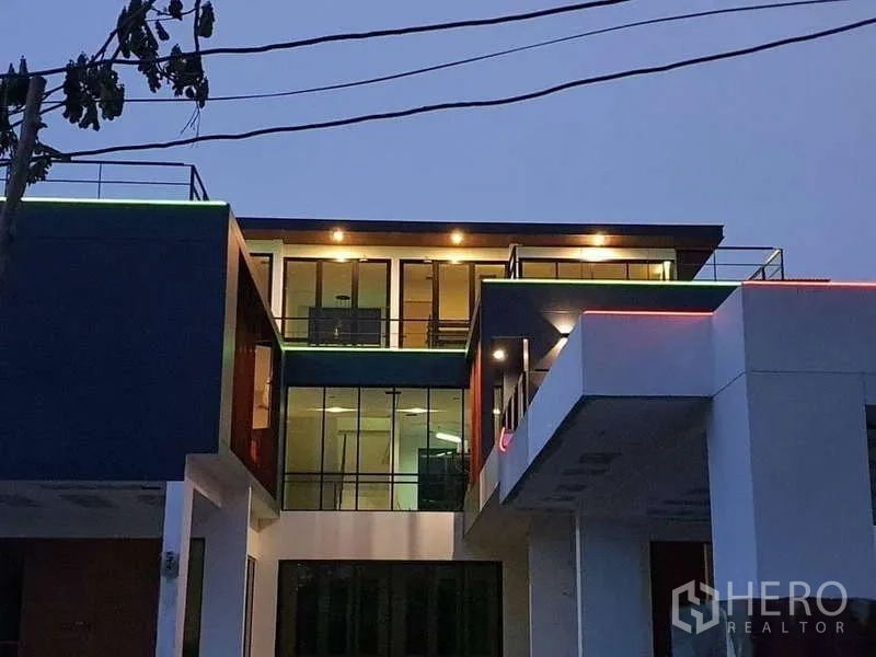 Detached House for rent in Phra Khanong, Bangkok - Night view of the facade with floor-to-ceiling windows and warm exterior lighting.