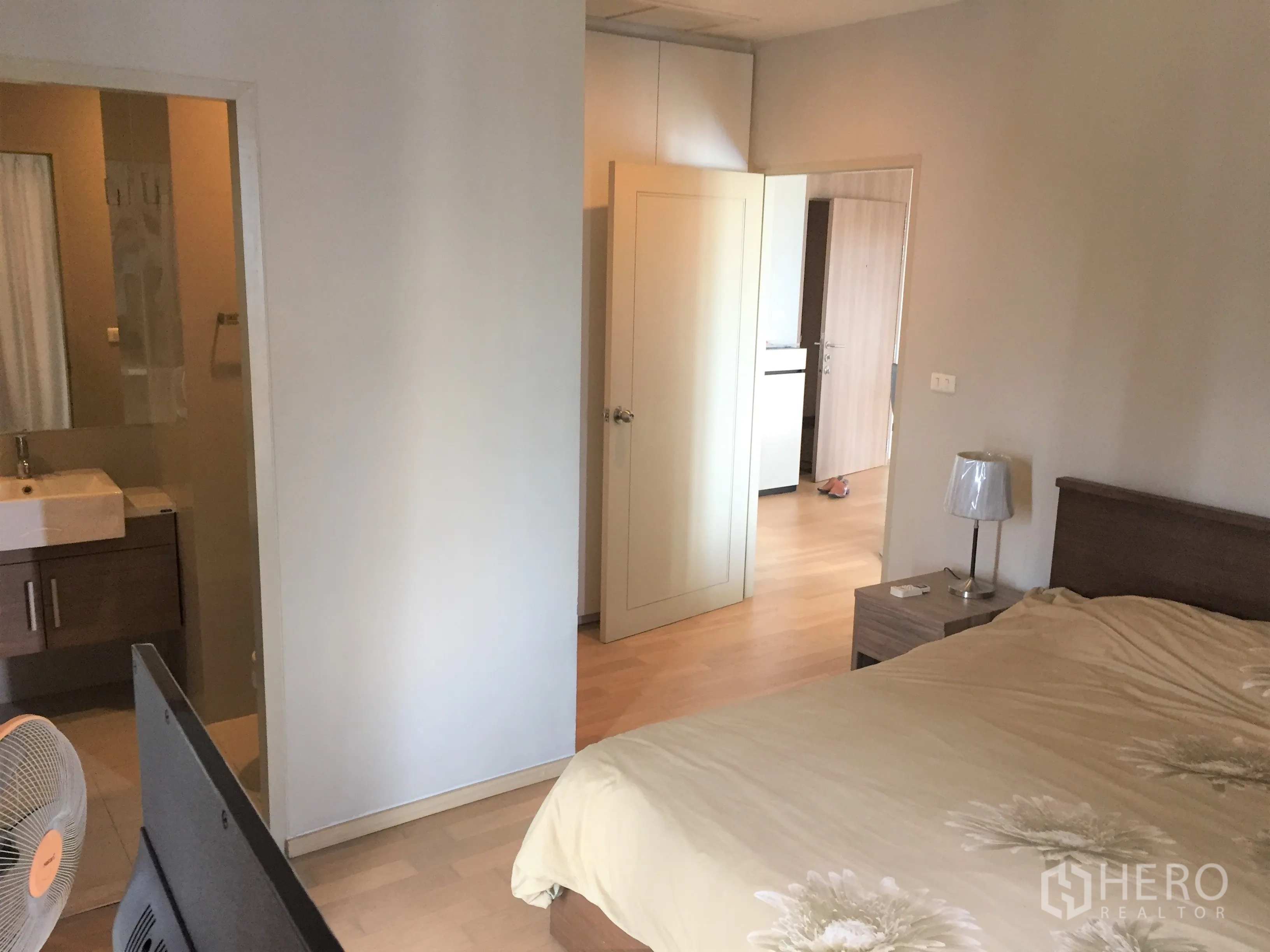 公寓 出租在Watthana, Bangkok - 主卧室，木地板、床头柜，并带有套内卫生间入口