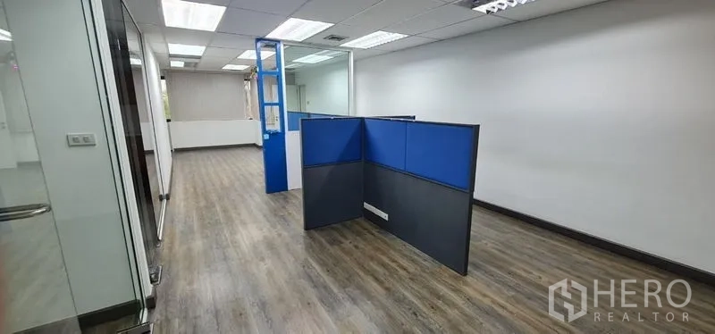 办公空间 出租在Watthana, Bangkok - 狭长工作区，蓝色隔板、木地板与吊顶灯。