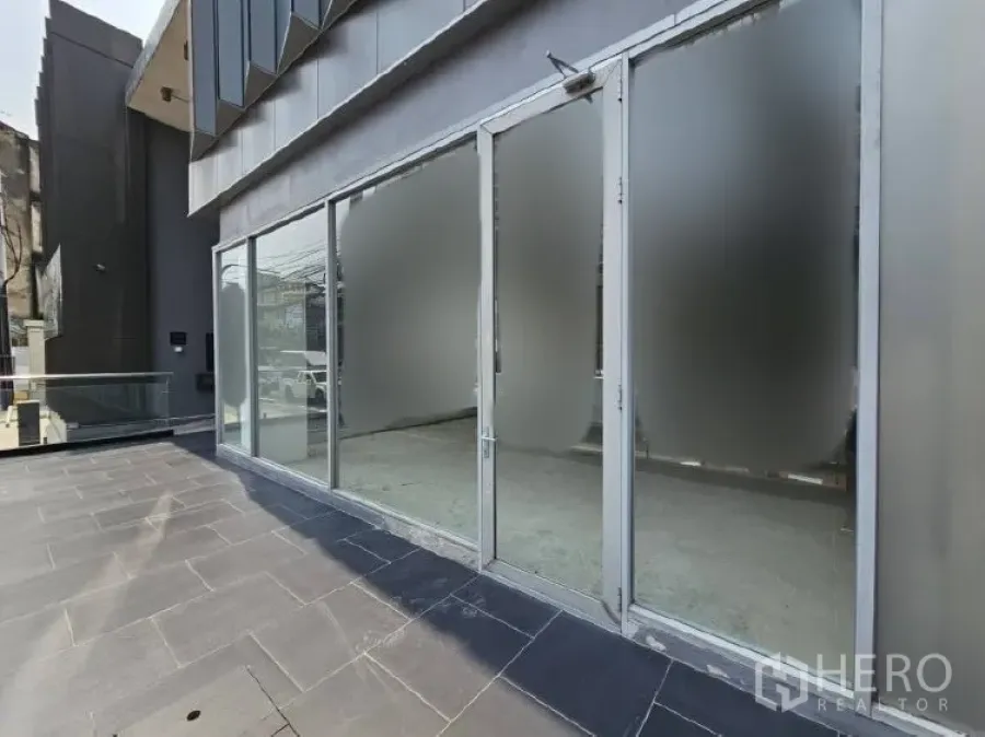 Retail Space for rent - Elevated retail storefront with full-height glass doors and a wide tiled terrace.