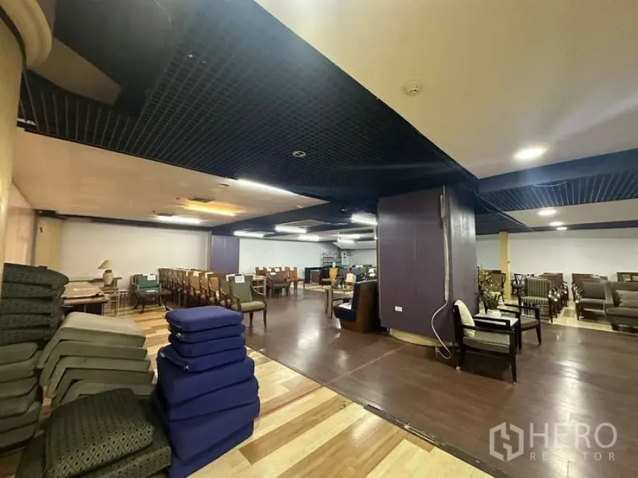 Retail Space for rent - Retail corner with stacked cushions, columns and multiple seating arrangements on two-tone wood flooring.