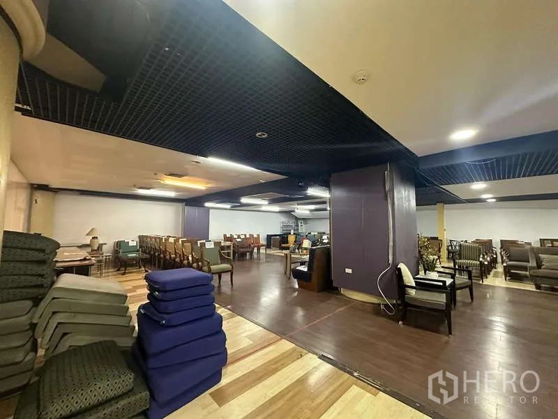 Retail Space for rent - Retail corner with stacked cushions, columns and multiple seating arrangements on two-tone wood flooring.
