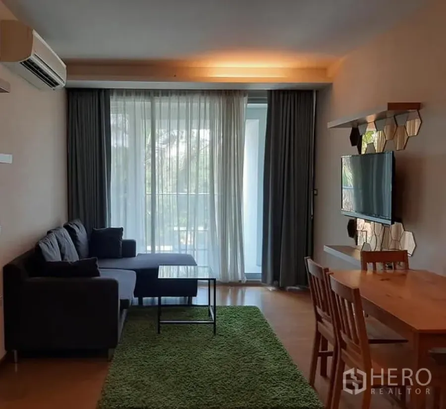 公寓 出售在Watthana, Bangkok - 明亮的客餐厅，沙发与电视墙，落地窗帘后连通阳台，位于瓦他那公寓。