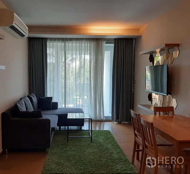 公寓 出售在Watthana, Bangkok - 明亮的客餐厅，沙发与电视墙，落地窗帘后连通阳台，位于瓦他那公寓。