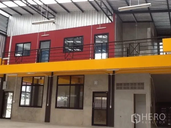 Warehouse for rent in Bang Kapi, Bangkok - Open-plan warehouse interior with high ceiling, skylights, a yellow mezzanine and red office rooms.