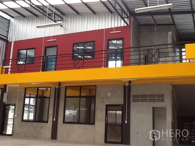 Warehouse for rent in Bang Kapi, Bangkok - Open-plan warehouse interior with high ceiling, skylights, a yellow mezzanine and red office rooms.