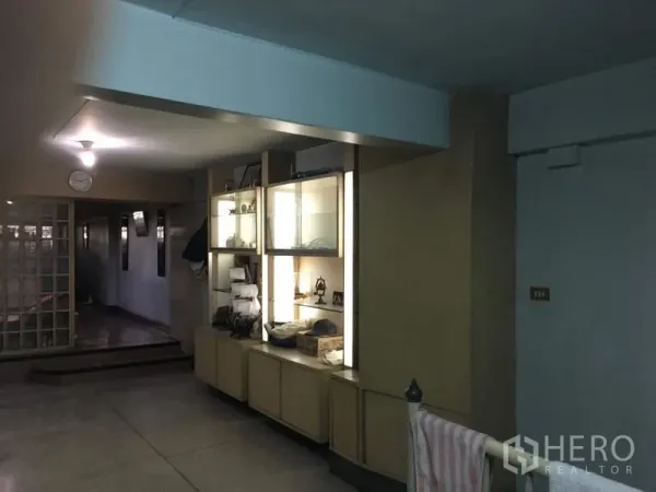 Shophouse for rent in Phra Khanong, Bangkok - Hallway featuring built-in illuminated display cabinets and a sliding glass partition.