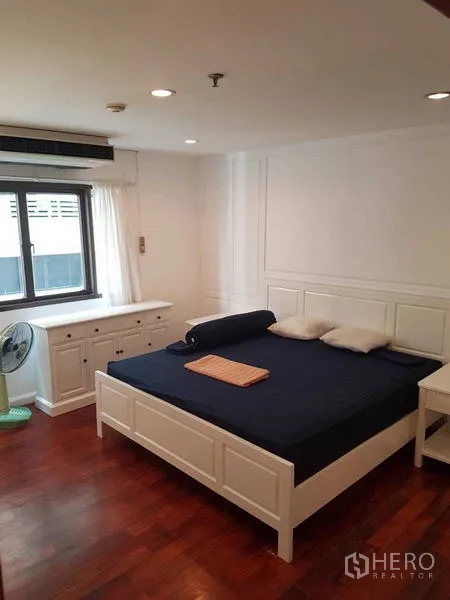 公寓 出租在Watthana, Bangkok - 主卧配白色床架、木地板与窗户，灯光明亮。