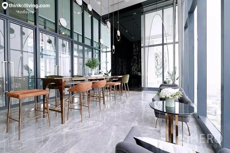 Condominium for rent in Watthana, Bangkok - Sky lounge dining area with long table, high stools and panoramic windows over the city.