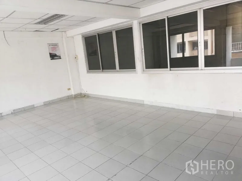 Factory for sale in Khlong Luang, Pathum Thani - Open office zone with a long row of windows and ceramic tile flooring.