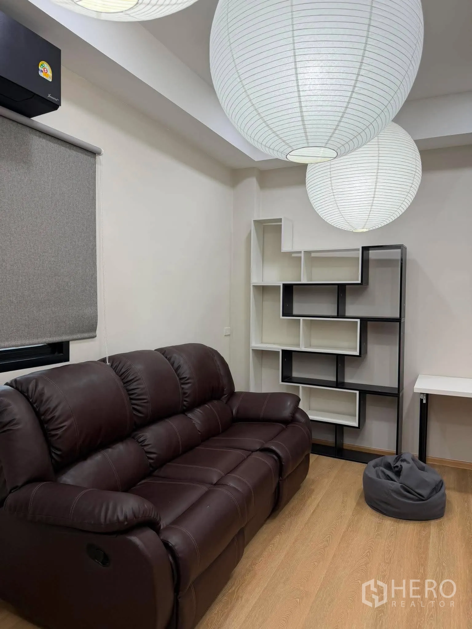 家庭办公室 for rent in Phra Khanong, Bangkok - 休闲角，深色皮沙发与展示架。