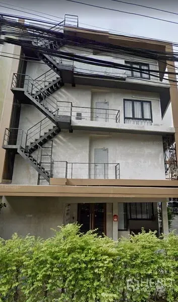 办公空间 出租在Phra Khanong, Bangkok - 四层办公楼外观，带外置金属逃生楼梯与前方绿篱，帕卡农