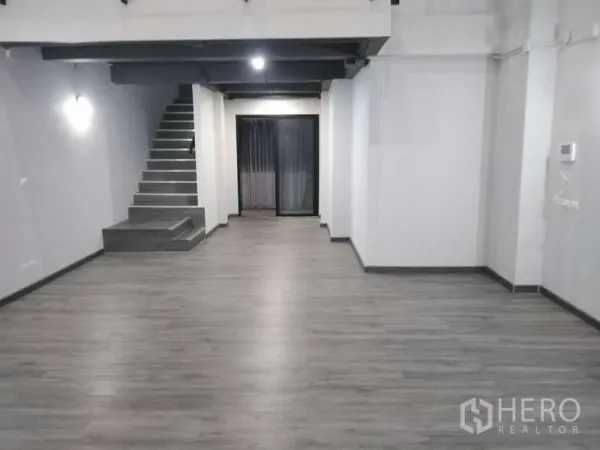 สำนักงานที่บ้าน ให้เช่าหรือขาย - พื้นที่ชั้นล่างแบบโอเพนสเปซกว้าง มีบันได พื้นสีเทา และประตูกระจกด้านหลัง