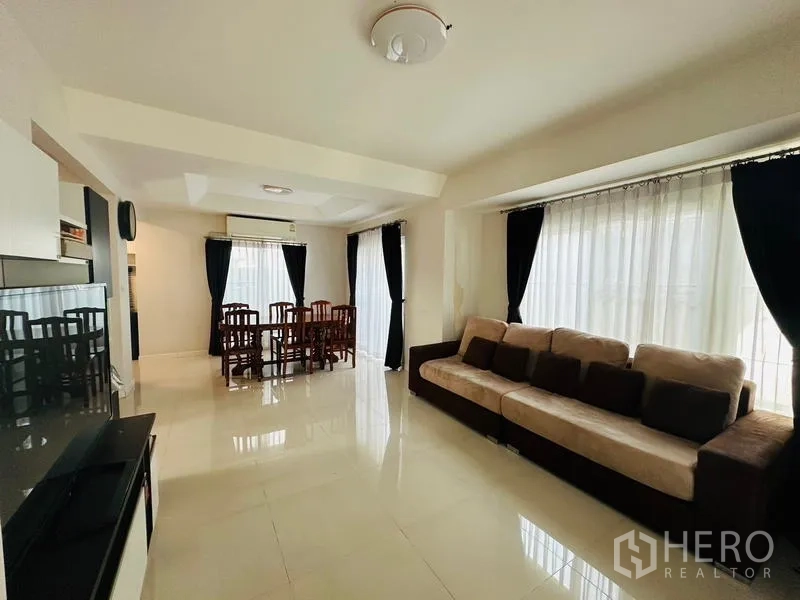 บ้าน ขายในPrawet, Bangkok - ห้องนั่งเล่นเชื่อมรับประทานอาหาร มีโซฟาตัวยาว หน้าต่างบานใหญ่และผ้าม่านทึบ.