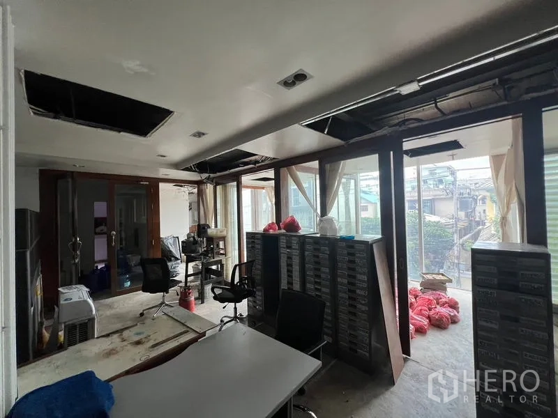 Retail Space for rent in Bang Rak, Bangkok - Open retail office area with storage racks and floor-to-ceiling glazing opening to a small terrace.