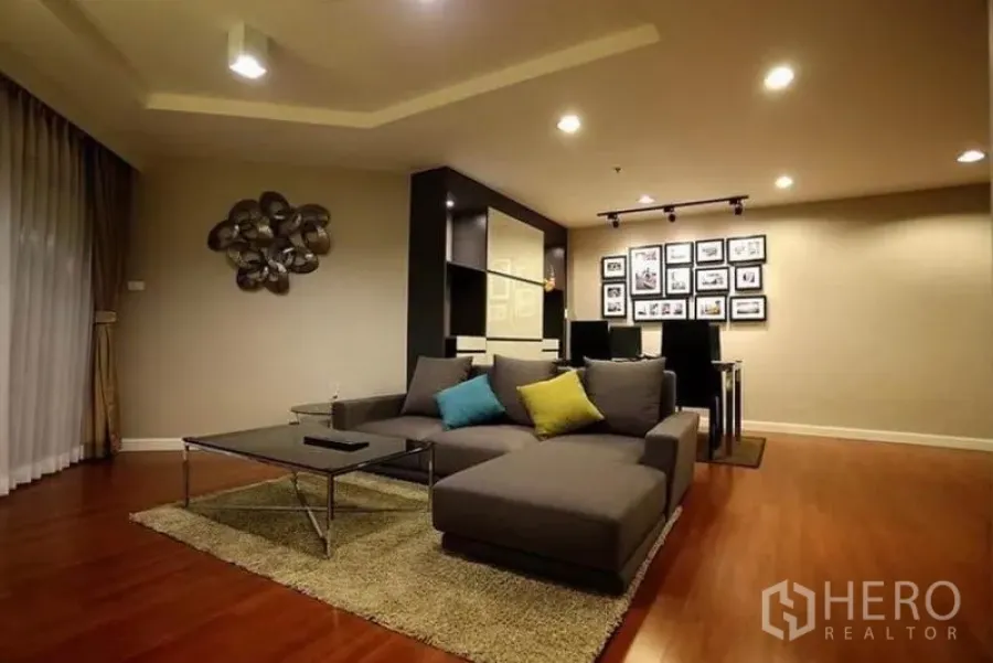 คอนโด ให้เช่าในHuai Khwang, Bangkok - ห้องนั่งเล่นโทนอุ่นของคอนโด 2 ห้องนอนในห้วยขวาง โซฟาเข้ามุม โต๊ะกลาง และพื้นไม้