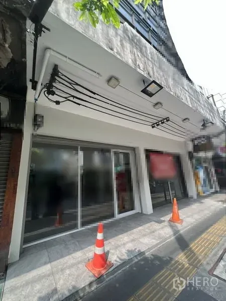 Shophouse for rent in Khlong Toei, Bangkok - Street-facing glass storefront with canopy lighting and tiled sidewalk on Sukhumvit Road.