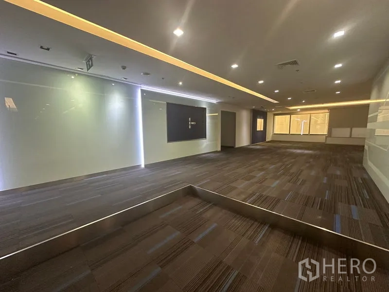 Office Space for rent in Khlong Toei, Bangkok - Reception or breakout area with accent strip lighting, carpet tiles, and a glass feature wall.