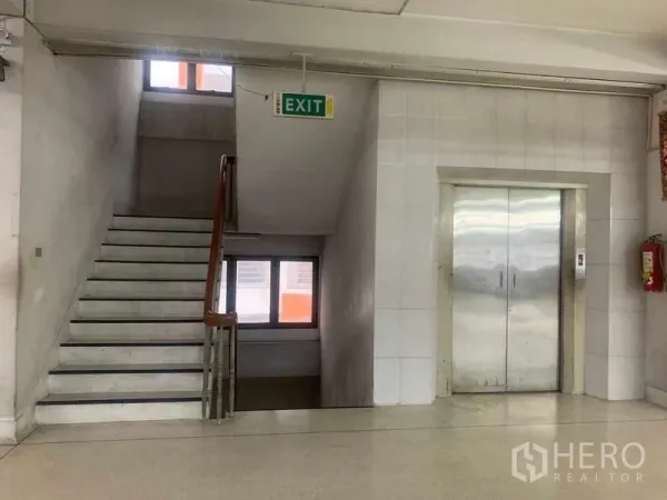 Office Space for rent in Khlong San, Bangkok - Stairwell beside a stainless-steel service elevator with an exit sign inside the office building.