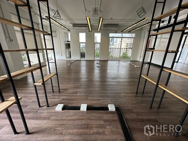 办公空间 出租在Watthana, Bangkok - 透过层架望向明亮办公室，设地面插座、吊灯和通阳台门。