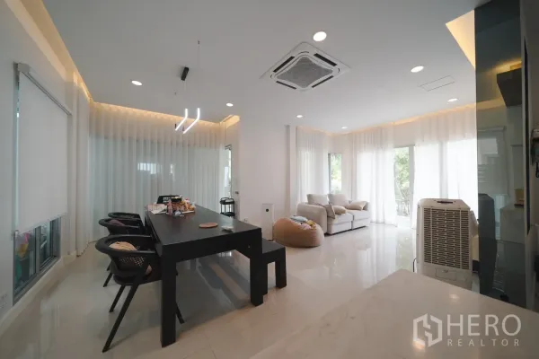 Detached House for rent or sale in Saphan Sung, Bangkok - Open‑plan living and dining area with a long table, pendant lights and a ceiling cassette air conditioner.