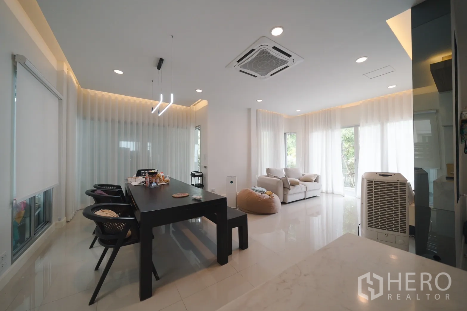 Detached House for rent or sale in Saphan Sung, Bangkok - Open‑plan living and dining area with a long table, pendant lights and a ceiling cassette air conditioner.