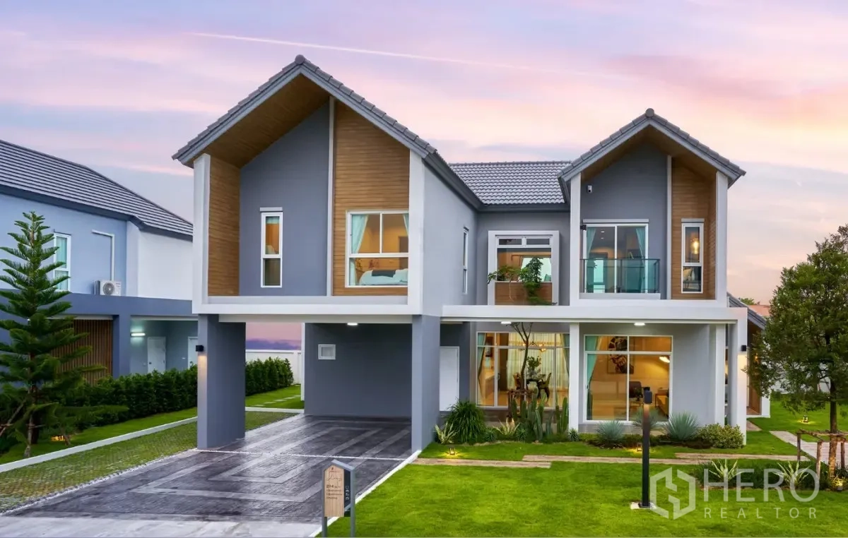 Detached House for rent in Lam Luk Ka, Pathum Thani - Contemporary two-storey detached house exterior at dusk with lawn and carport.