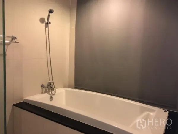 公寓 出租在Pathum Wan, Bangkok - 浴室内置浴缸与手持花洒，瓷砖墙面。