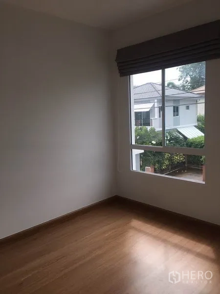 Detached House for rent in Suan Luang, Bangkok - Empty bedroom with large window overlooking neighboring homes and greenery.