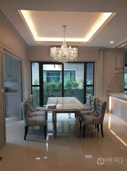 独立式住宅 出租或出售在Prawet, Bangkok - 餐厅设水晶吊灯与石材餐桌，落地滑门望向花园
