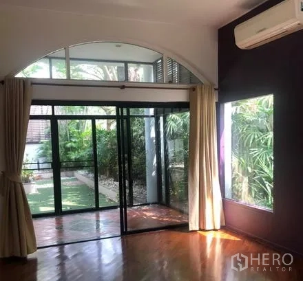 Detached House for rent in Bang Rak, Bangkok - Sunlit room with sliding doors to the garden and wall-mounted air conditioner.