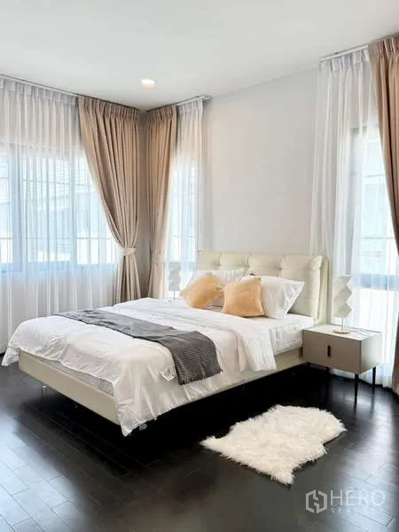 Detached House for rent or sale in Bang Phli, Samut Prakan - Bright bedroom with padded headboard, bedside tables and fluffy rug on dark wood floors.