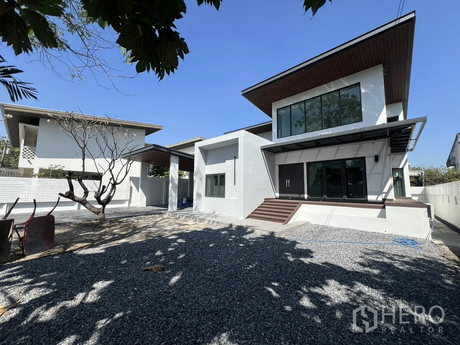 Detached House for rent in Saphan Sung, Bangkok - Contemporary white detached house with large yard and gravel garden under a blue sky.