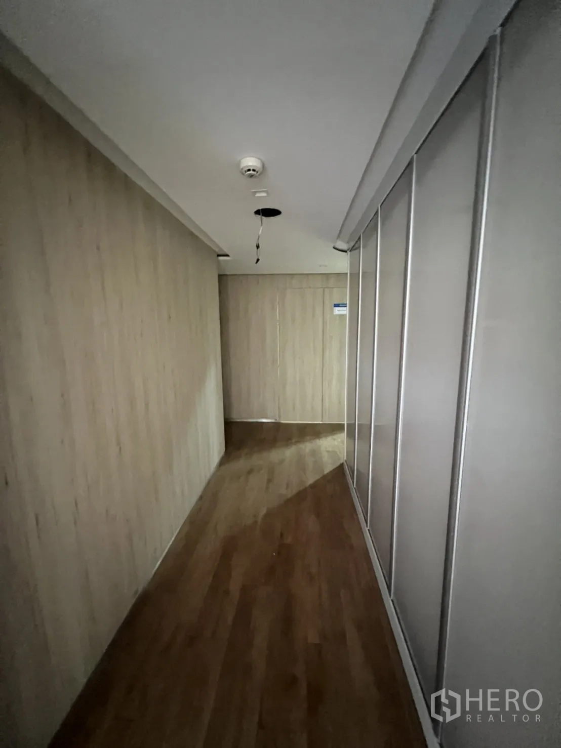 Shophouse for rent or sale in Watthana, Bangkok - Hallway with wood panels and sliding wardrobe doors.
