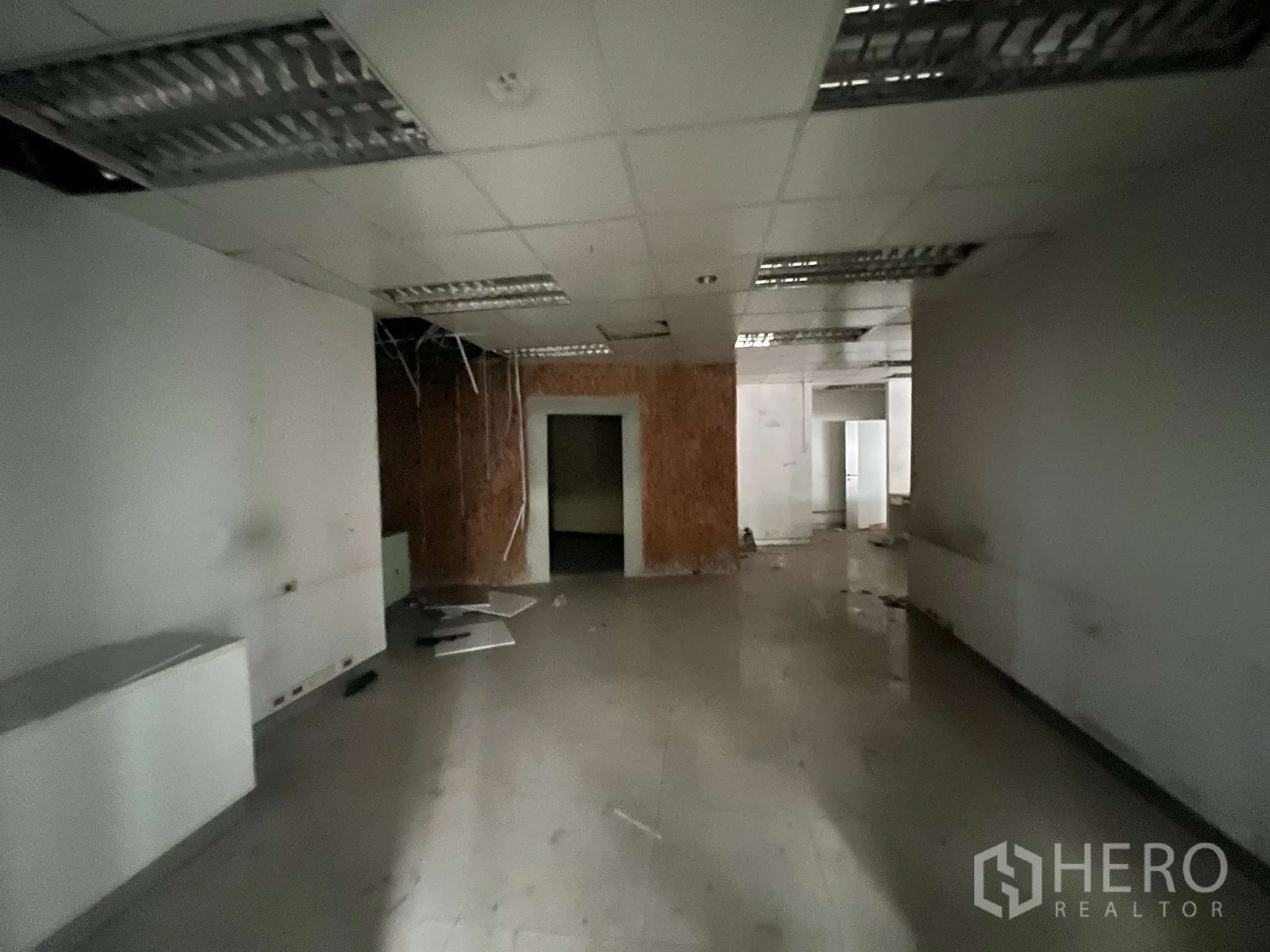 Shophouse for rent or sale in Khlong Toei, Bangkok - Rear section of the premises with suspended ceiling, exposed wiring, and a storage room.