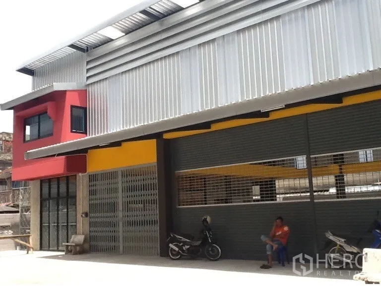 Warehouse for rent in Bang Kapi, Bangkok - Contemporary warehouse frontage with large shutters and a sheltered apron for parking.