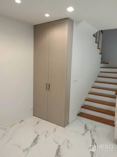 Townhouse for rent in Yan Nawa, Bangkok - Under‑stair storage cabinet beside wood‑step staircase.