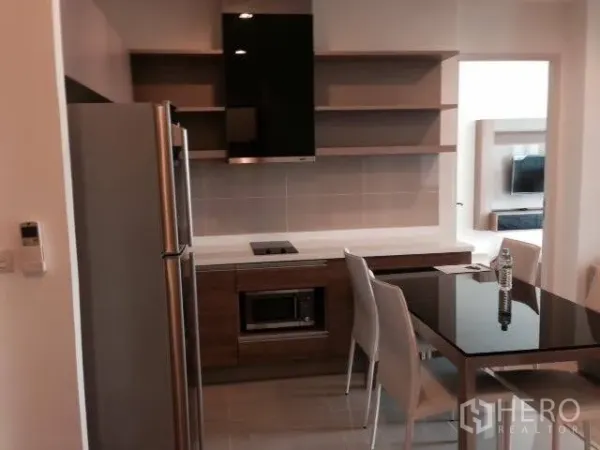 Condominium for rent in Khlong Toei, Bangkok - Kitchen area featuring stainless refrigerator, range hood, microwave, open shelving, and a dining set.