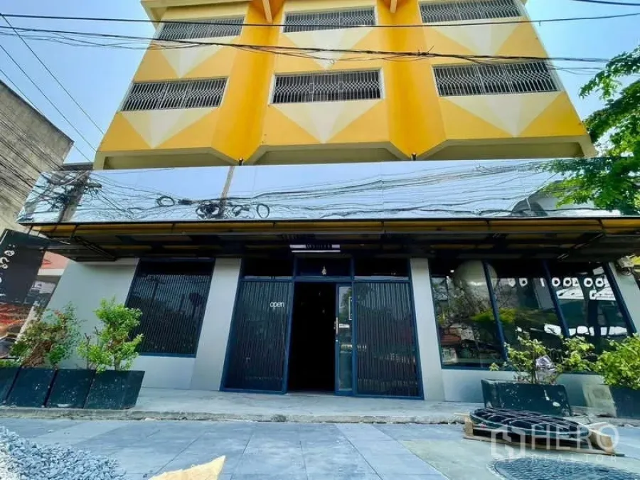 店屋 出租在Lat Phrao, Bangkok - 曼谷拉抛黄色与灰色四层店屋外立面，整面玻璃与花槽。