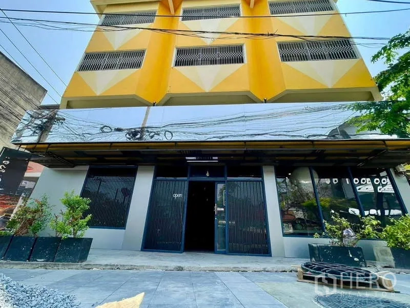 店屋 出租在Lat Phrao, Bangkok - 曼谷拉抛黄色与灰色四层店屋外立面，整面玻璃与花槽。