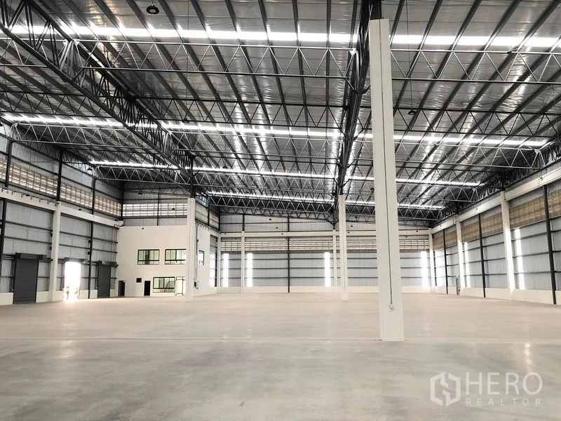 Factory for rent in Samut Prakan - Utility corner featuring electrical control panels next to a staff restroom inside the warehouse.