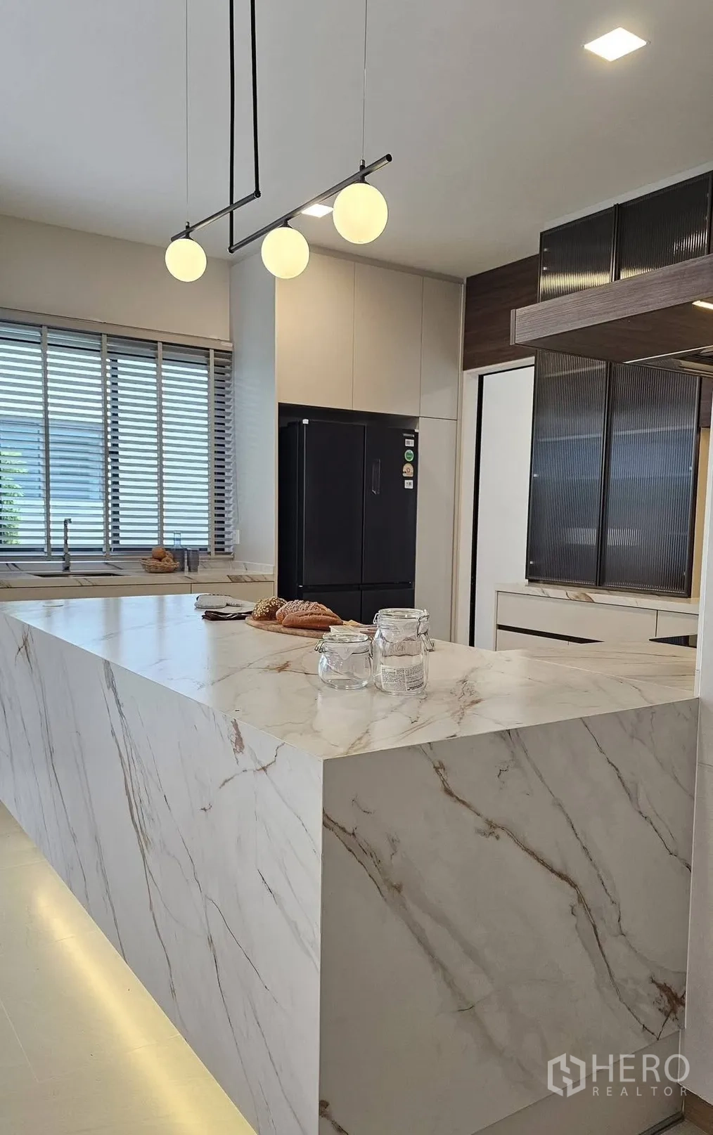 独栋房屋 for rent in Bang Phli, Samut Prakan - 简洁厨房，瀑布式大理石中岛、吊灯与黑色冰箱。