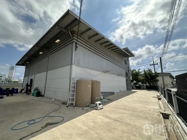 Factory for rent or sale in Pathum Thani - Side view of steel-clad warehouse with wide concrete yard for loading.