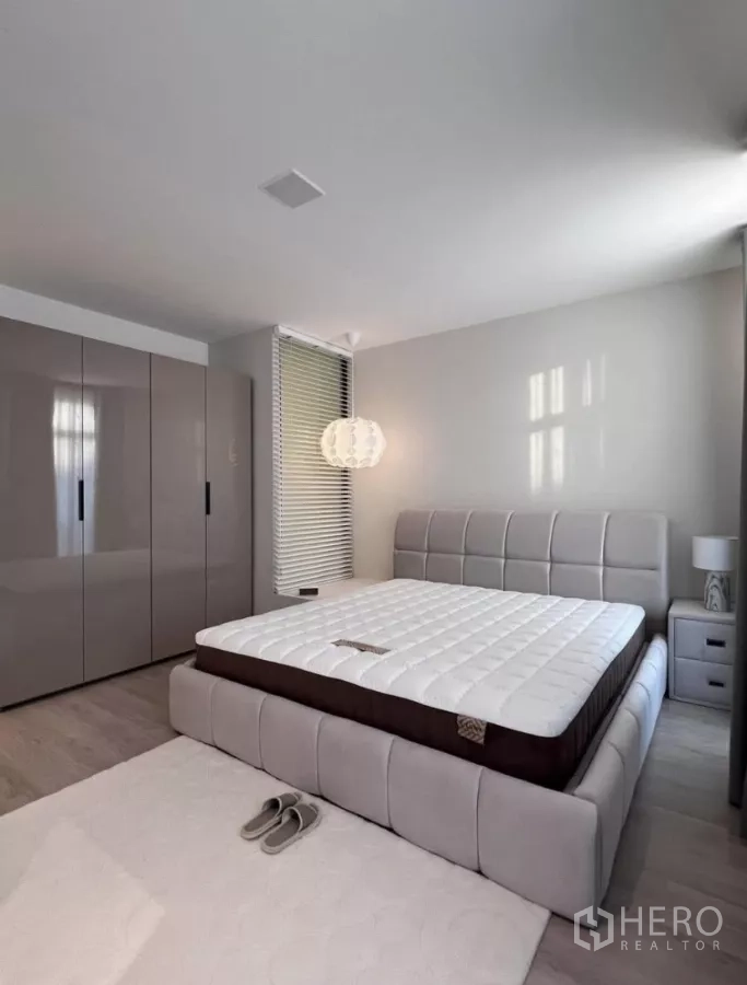 Townhouse for rent in Bang Phli, Samut Prakan - Master bedroom with upholstered bedframe, glossy wardrobes, bedside tables and soft lighting.