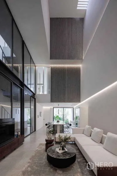 带办公室的家 出租在Bang Phli, Samut Prakan - 时尚挑高客厅，转角沙发、格栅装饰墙与大面积玻璃。